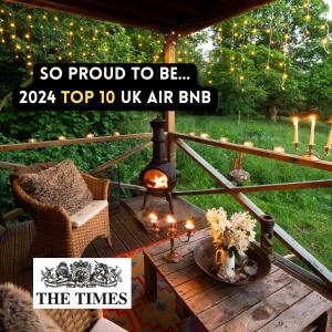 a table with a fireplace on a patio with lights at Luxury Off-Grid Cabin with Outdoor Bath in Scotland in Clachan of Campsie