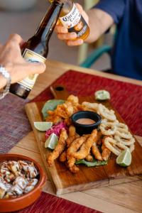 a person holding a bottle of beer and a plate of food at Hotel Boutique Can Cocal El Cuyo in El Cuyo