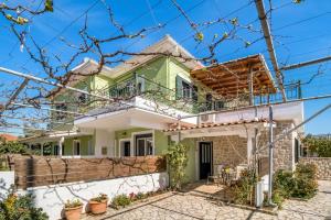 a green and white house with a fence at Dionysia Rooms in Lefkada