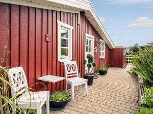 a red building with two white chairs and a table at Holiday Home Gesine - 50m to the inlet by Interhome in Børkop