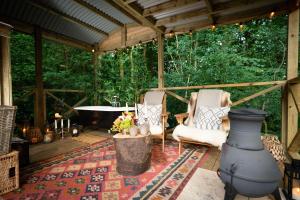 a screened in porch with a tub and two chairs at The Green Wagon at FINGLEN with gorgeous Outdoor Bath in Glasgow