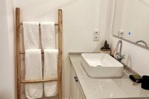 a white bathroom with a sink and towels at Stunning beach apartment in Almancil +10 photos