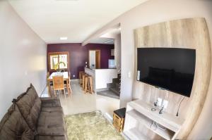 sala de estar con TV de pantalla plana grande en la pared en Casas dos Alpes en Gramado