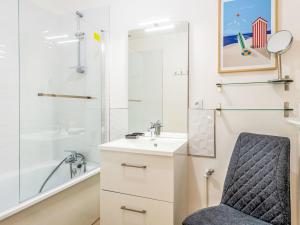 a bathroom with a sink and a shower and a chair at Holiday Home La Berckoise by Interhome in Berck-sur-Mer