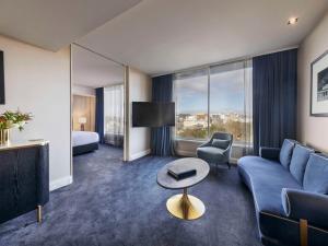 奥克兰Pullman Auckland Hotel & Apartments的酒店客房配有蓝色的沙发和床。