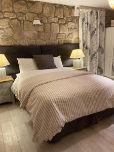 a bedroom with a large bed with a stone wall at Idyllic French farmhouse in Les Assions