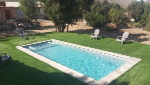 a swimming pool in a yard with chairs on the grass at Refugio el Amparo de Paine in El Majuelo