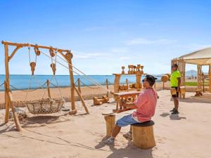 a man sitting on a stump on the beach at Rixos Premium Seagate in Sharm El Sheikh