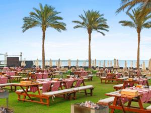 a beach with tables and chairs and palm trees at Rixos Premium Seagate in Sharm El Sheikh