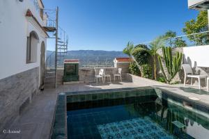 a swimming pool with a table and chairs next to a house at Casa maravillosa in Chefchaouen