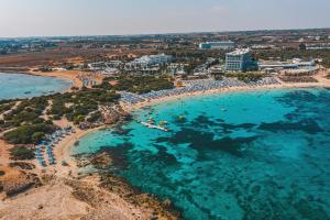 una vista aerea di una spiaggia con acqua blu di Dome Beach Marina Hotel & Resort a Ayia Napa Altre 171 foto