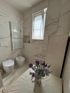 a bathroom with a sink and a toilet and a vase of flowers at Casa di Nonna in Manfredonia +13 photos