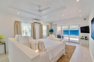 a white bedroom with a white bed and a view of the ocean at Solaris Beach House - Beachfront Property, St James in Saint James