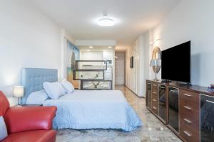 ein Schlafzimmer mit einem Bett und einem Flachbildfernseher in der Unterkunft Golden Beach Luxury Las Canteras in Las Palmas de Gran Canaria + 14 Fotos