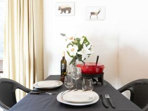 een zwarte tafel met borden en glazen en een vaas met bloemen bij Apartment Gamat 49 by Interhome in Villars-sur-Ollon