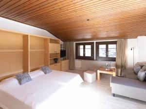 een slaapkamer met een groot wit bed en een bank bij Apartment Gamat 49 by Interhome in Villars-sur-Ollon +18 foto's