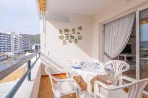 a white dining room with a table and chairs on a balcony at Sol in Port d'Alcudia