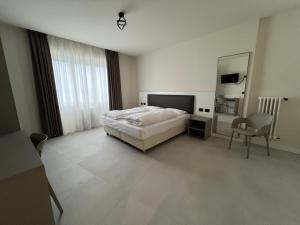 a bedroom with a bed and a chair and a mirror at Hotel Villa Margherita in Limone sul Garda