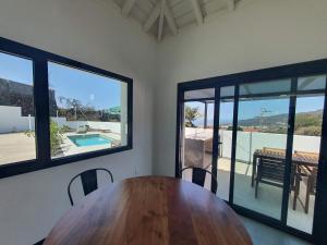 a dining room with a wooden table and large windows at Casa Fielato in Los Barros