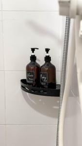 Taiping Chill Retreat Homestay near Lake Garden في تايبينغ: زجاجتان من الصابون جالستان على رف في الحمام