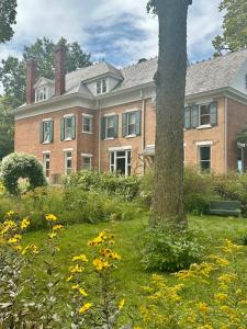 a large brick building with a tree in the yard at Historic Manor Overlooking Park in Bloomington