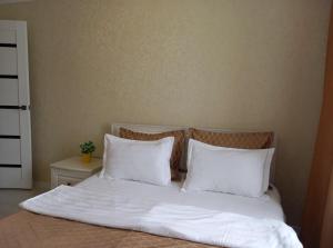 un lit avec des draps blancs et des oreillers dans une chambre dans l'établissement Космос-Лайт, à Aqtöbe