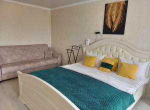 - un lit avec des oreillers jaunes et verts et un canapé dans l'établissement Космос-Лайт, à Aqtöbe