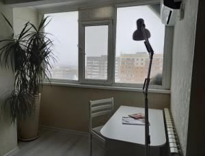 une chambre avec une table, une lampe et une fenêtre dans l'établissement Космос-Лайт, à Aqtöbe