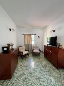 a living room with a tv and a couch and chairs at Casa en alquiler temporario in Ramallo