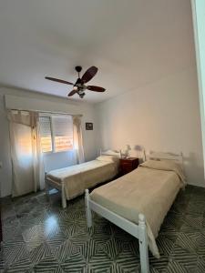 a bedroom with two beds and a ceiling fan at Casa en alquiler temporario in Ramallo