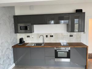 a kitchen with black cabinets and a sink at Alba Apartment Central Pitlochry in Pitlochry