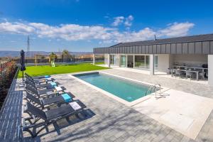 Una piscina con tumbonas y una casa. en Villa Santila, en Labin