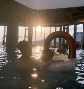 a man and a child in a swimming pool at A La Carte Ha Long Oceanview Fireworksview Panoramic 2BR2WC suite with balcony in Ha Long
