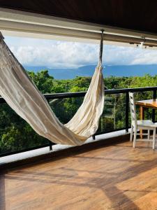 a hammock on a balcony with a view of the forest at Riviera 200m Praia Serv de Praia and Pisc Aquec in Bertioga