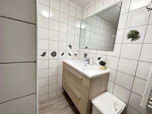 a bathroom with a sink and a toilet and a mirror at Les 3 Piliers grand T2 confortable avec parking in Reims +29 photos