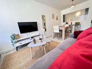 a living room with a couch and a flat screen tv at Les 3 Piliers grand T2 confortable avec parking in Reims