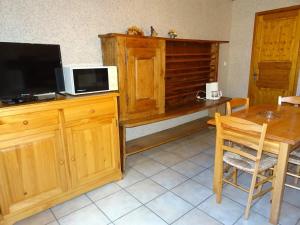 cocina con escritorio de madera, TV y mesa en Les Oulles 9, en La Chapelle-en-Valgodemard