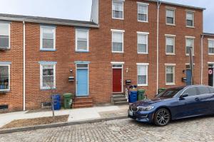 a blue car parked in front of a brick building at Modern 3BR Retreat with BBQ & Smart TV in Baltimore