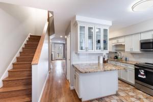 a kitchen with white cabinets and a staircase at Modern 3BR Retreat with BBQ & Smart TV in Baltimore