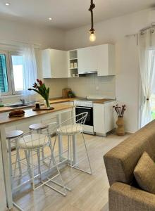 a kitchen with white cabinets and bar stools at Casa Daphne in (( Agía Eleoúsa ))
