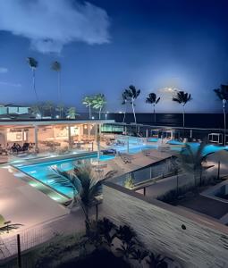 a view of a pool at night with palm trees at Cais Eco Residência in Porto De Galinhas