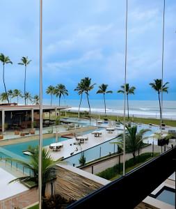 a view of a resort with palm trees and the ocean at Cais Eco Residência in Porto De Galinhas