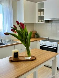 a vase with red flowers on a wooden table in a kitchen at Casa Daphne in (( Agía Eleoúsa )) +8 photos