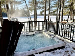 a hot tub in the snow with a fence at Quiet Maine Cabin Getaway in Lebanon