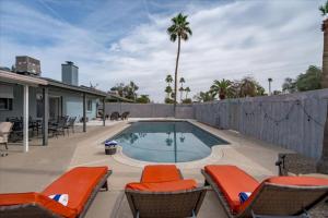 a swimming pool with chairs and a fence at The Palm House Tempe in Tempe