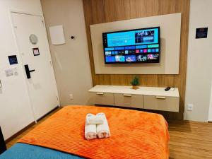 a bedroom with a bed with a towel and a tv at Modern Studio in Catete – Close to the Metro in Rio de Janeiro