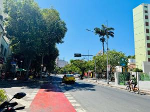 a person riding a bike down a street with a yellow car at Modern Studio in Catete – Close to the Metro in Rio de Janeiro