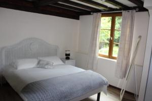 a white bedroom with a bed and a window at Les Bambous, avec piscine, tennis et lac privatif in Guerquesalles +39 photos