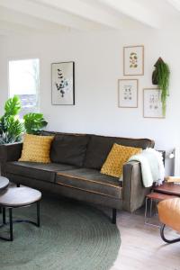 ein Wohnzimmer mit einem braunen Ledersofa in der Unterkunft Cozy cottage in the heart of the Veluwe in Putten