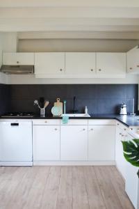 eine Küche mit weißen Schränken und einem Holzboden in der Unterkunft Cozy cottage in the heart of the Veluwe in Putten + 19 Fotos